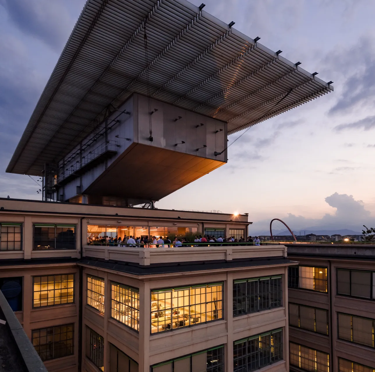 Padiglione panoramico Renzo Piano sul tetto del Lingotto Torino al tramonto, con persone sulla terrazza e luci accese