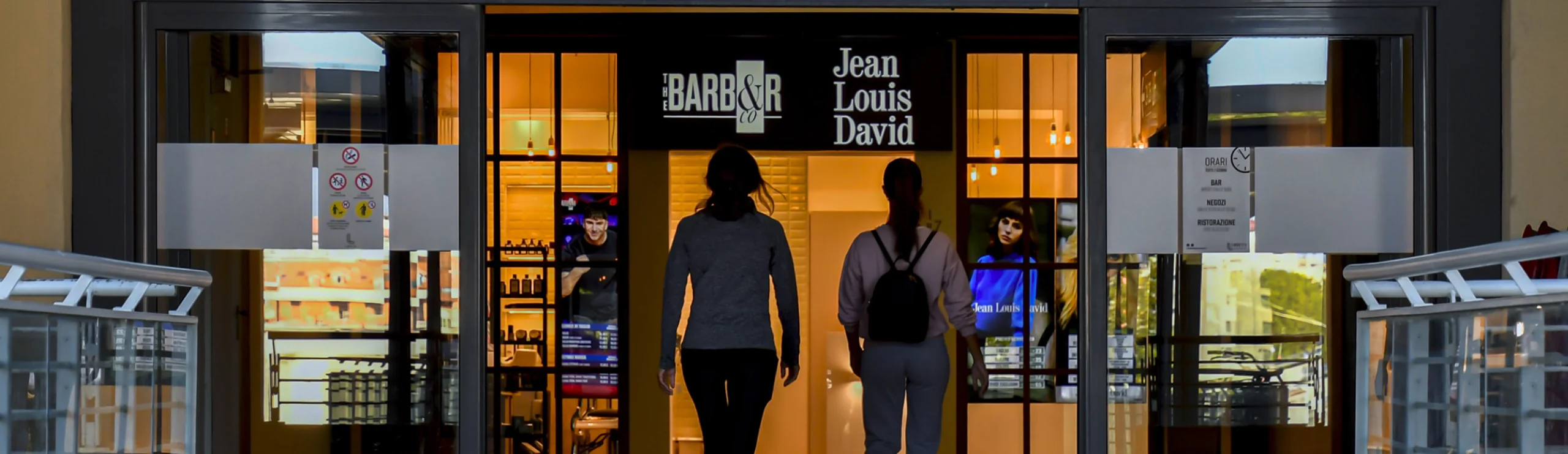 Ingresso di parrucchiere e barberia The Barber & Co Jean Louis David con due persone che accedono.