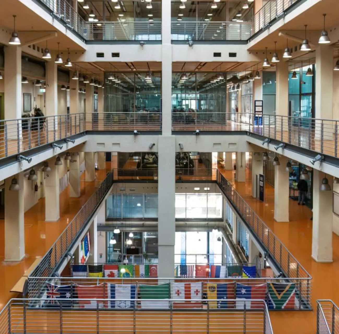 Interno moderno e luminoso del centro congressi Lingotto Torino, con bandiere internazionali esposte e corridoi su più livelli.